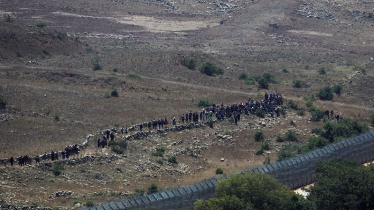 مدنيون سوريون يقتربون من السياج الحدودي بالجولان