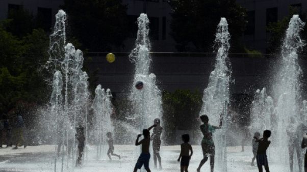 Des enfants jouent au milieu de jets d'eau à Paris le 26 juillet 2018. Des enfants jouent au milieu de jets d'eau à Paris le 26 juillet 2018.