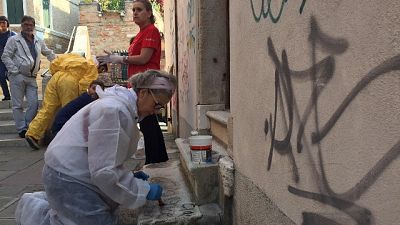 Veneziani puliscono pietre da graffiti