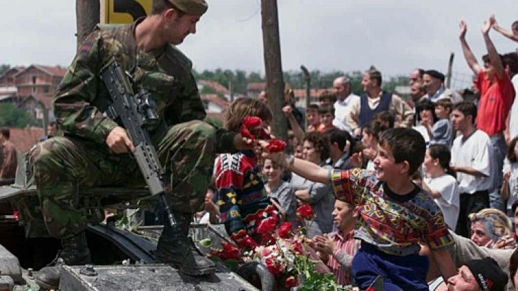 Un enfant albanais offre des roses à un soldat britannique membre des forces de l'OTAN qui se déploient à Pristina, au Kosovo, le 13 juin 1999