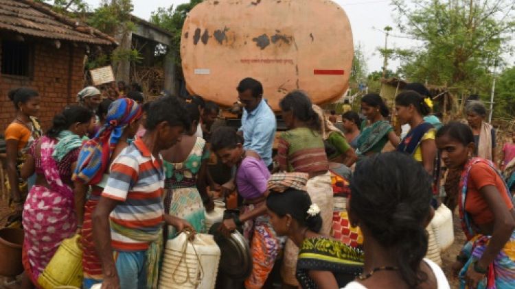 Des villageois remplissent des bidons d'eau livrée par camion citerne, dans le village indien de Shakar Pada, le 10 juin 2019