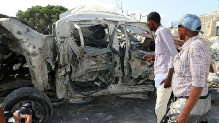Des personnes à côté de l'épave d'une voiture sur le lieu d'une explosion à Mogadiscio le 15 juin 2019