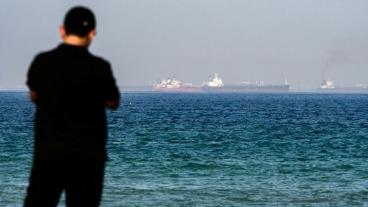 Une photo prise le 15 juin 2019 montre un homme avec au loin un pétrolier dans les eaux du Golfe au large des Emirats arabes unis