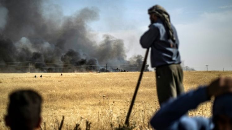 Des hommes devant un champ de blé en feu dans la province de Hassaké en Syrie, le 11 juin 2019