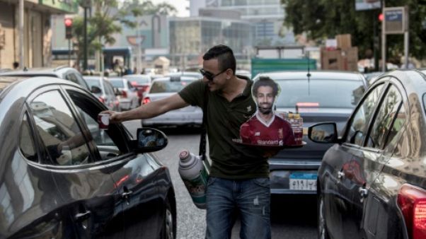 Un vendeur ambulant de café ou de thé, portrait de Mohamed Salah en main, dans les rues du Caire, le 17 juin 2019 Un vendeur ambulant de café ou de thé, portrait de Mohamed Salah en main, dans les rues du Caire, le 17 juin 2019