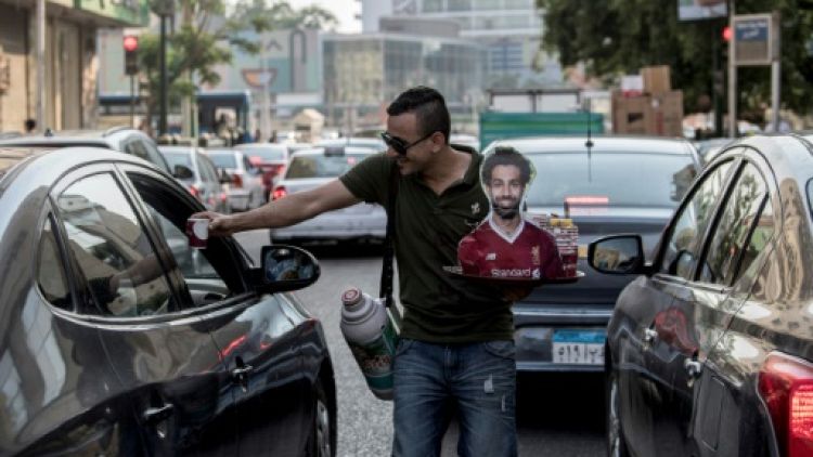 Un vendeur ambulant de café ou de thé, portrait de Mohamed Salah en main, dans les rues du Caire, le 17 juin 2019 