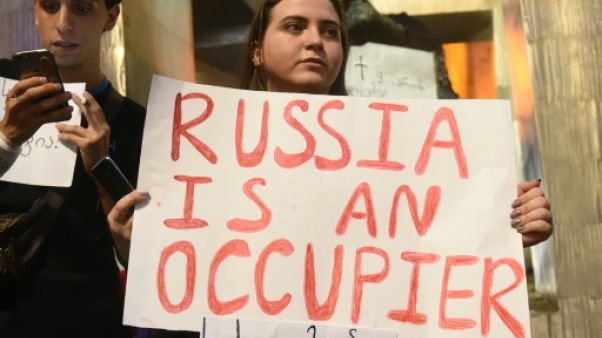 Une protestataire porte une pancarte avec le slogan "La Russie est un occupant" devant le Parlement géorgien à Tbilissi, le 20 juin 2019 Une protestataire porte une pancarte avec le slogan "La Russie est un occupant" devant le Parlement géorgien à Tbilissi, le 20 juin 2019