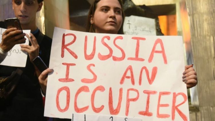 Une protestataire porte une pancarte avec le slogan "La Russie est un occupant" devant le Parlement géorgien à Tbilissi, le 20 juin 2019