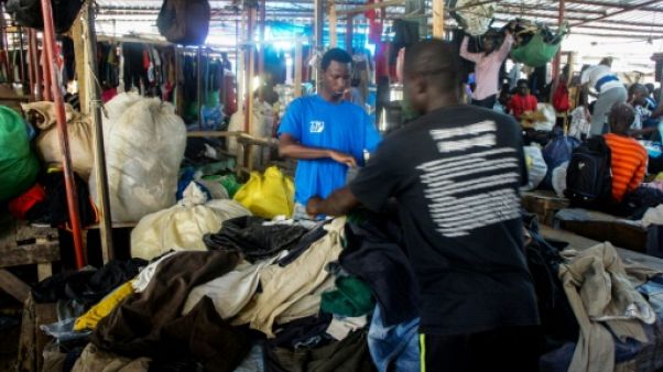 Mamadou Sarr (g), 23 ans, prépare son stand de vêtements d'occasion sur le marché de Colobane, à Dakar, le 25 juin 2019 Mamadou Sarr (g), 23 ans, prépare son stand de vêtements d'occasion sur le marché de Colobane, à Dakar, le 25 juin 2019