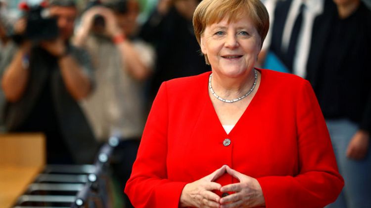 Germany's Merkel, planning to serve full term, backs under-fire protegee