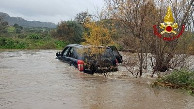 Tre persone con un fuoristrada attraversano torrente ingrossato Tre persone con un fuoristrada attraversano torrente ingrossato
