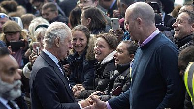 El Rey Carlos da la mano y conversa con personas que hacen fila para despedirse de Isabel